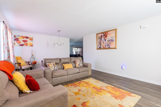 living area with an inviting chandelier, a textured ceiling, baseboards, and wood finished floors