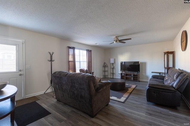 living room with a textured ceiling, dark wood-style floors, baseboards, and a ceiling fan