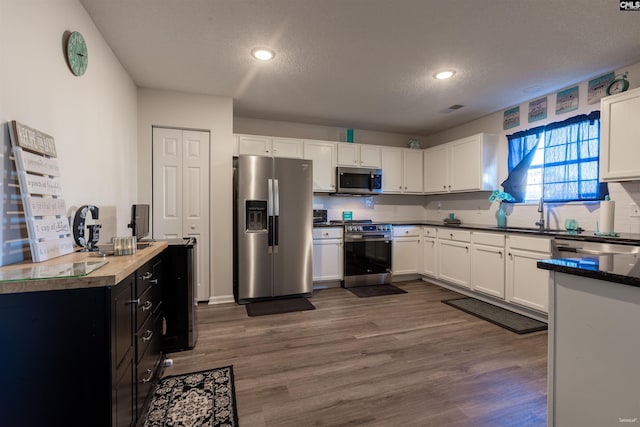 kitchen with decorative backsplash, dark wood-style floors, stainless steel appliances, and white cabinets