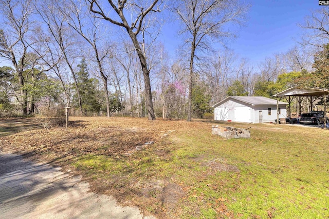 view of yard featuring an outdoor structure, a carport, and a garage