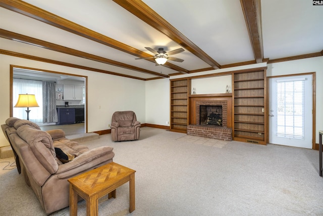 living area with beamed ceiling, ceiling fan, ornamental molding, and a brick fireplace