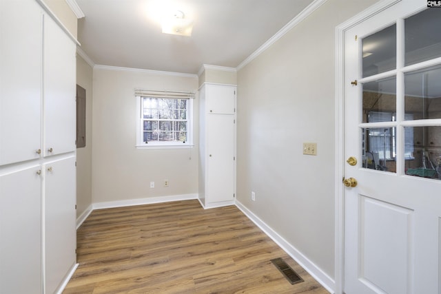 interior space with light wood-type flooring, baseboards, visible vents, and crown molding