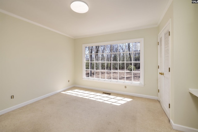 carpeted spare room featuring baseboards, visible vents, and ornamental molding