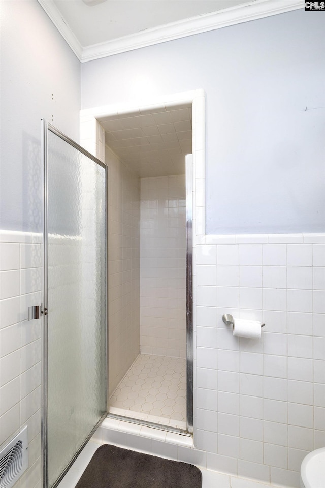 bathroom with a stall shower, visible vents, crown molding, and tile walls