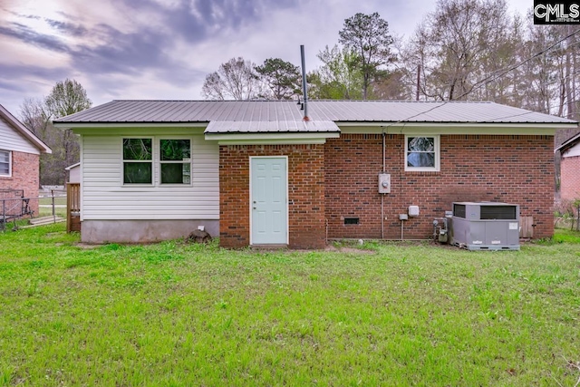 4104 Candlelite Dr, Columbia, SC 29209 - back of house featuring central air condition unit, fence, brick siding, metal roof, and a lawn