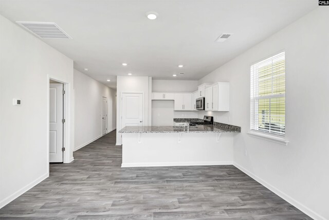 130 Shumard Ct, Columbia, SC 29203 - kitchen featuring stove, stainless steel microwave, dark stone countertops, visible vents, and a peninsula