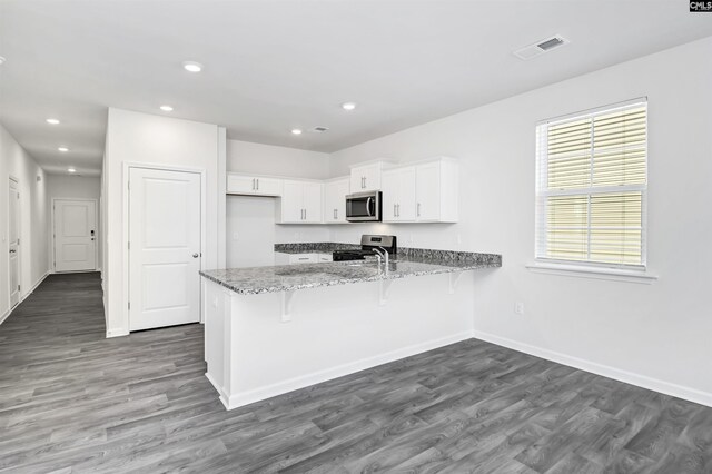 130 Shumard Ct, Columbia, SC 29203 - kitchen with stainless steel appliances, light stone counters, visible vents, white cabinets, and a peninsula