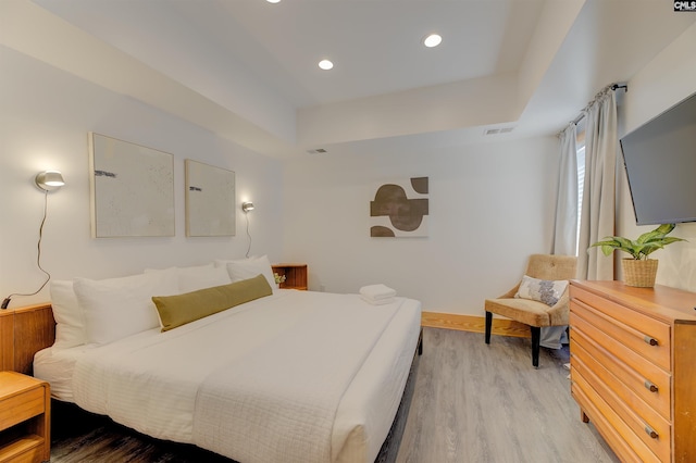 bedroom with visible vents, wood finished floors, recessed lighting, and a raised ceiling