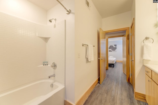 bathroom featuring bathtub / shower combination, vanity, wood finished floors, baseboards, and visible vents