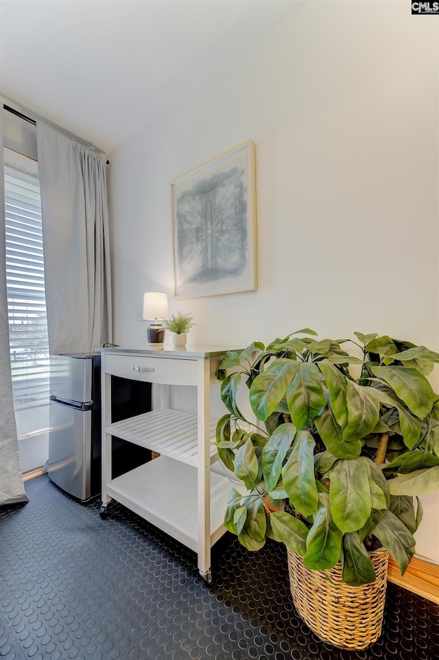 bedroom featuring freestanding refrigerator and dark colored carpet