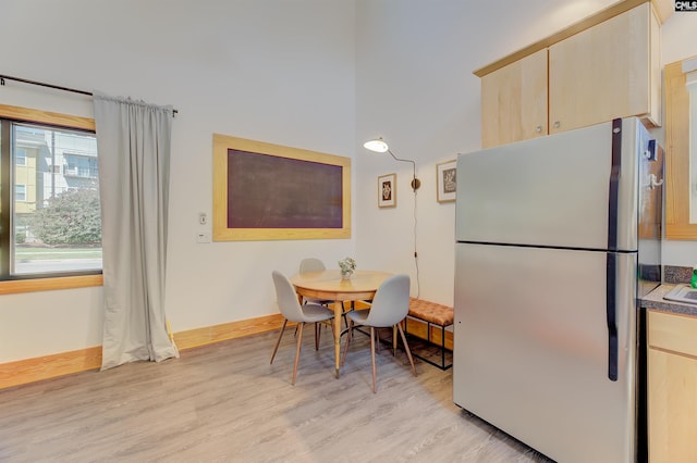 dining space featuring baseboards and light wood-style floors