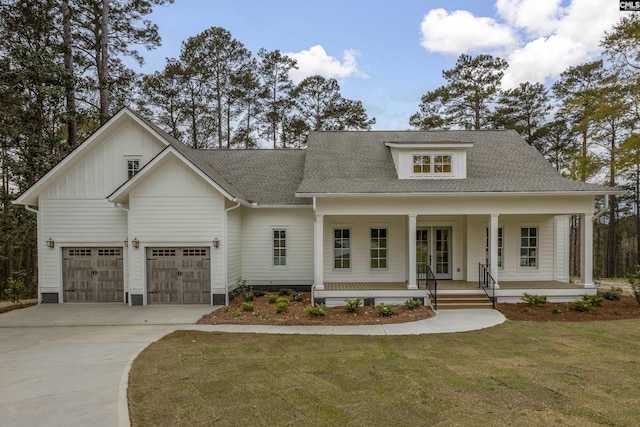 view of front of home featuring a garage, a front lawn, driveway, french doors, and a porch