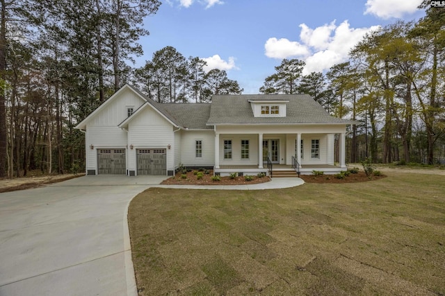 view of front of house featuring driveway, covered porch, a garage, and a front lawn