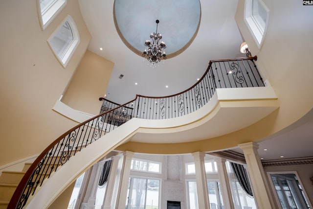 stairway featuring decorative columns, a high ceiling, recessed lighting, and a chandelier
