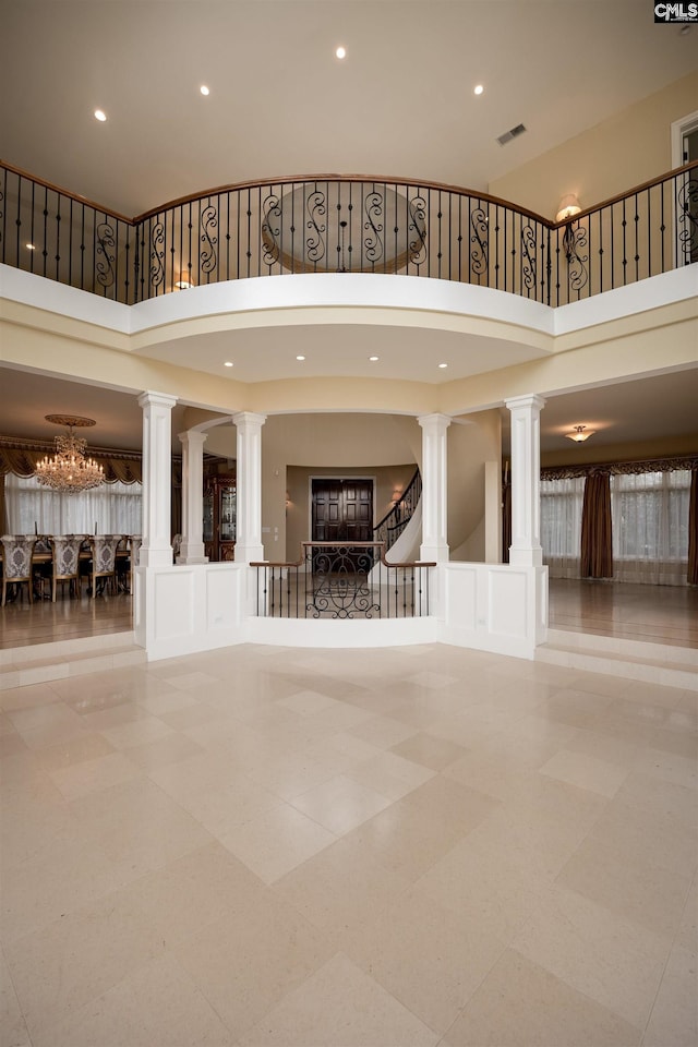 interior space featuring decorative columns, visible vents, recessed lighting, and an inviting chandelier