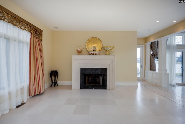 unfurnished living room featuring decorative columns, a fireplace, recessed lighting, and baseboards