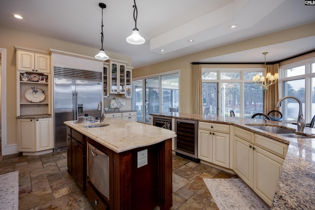 kitchen with cream cabinets, a sink, stone tile floors, and wine cooler
