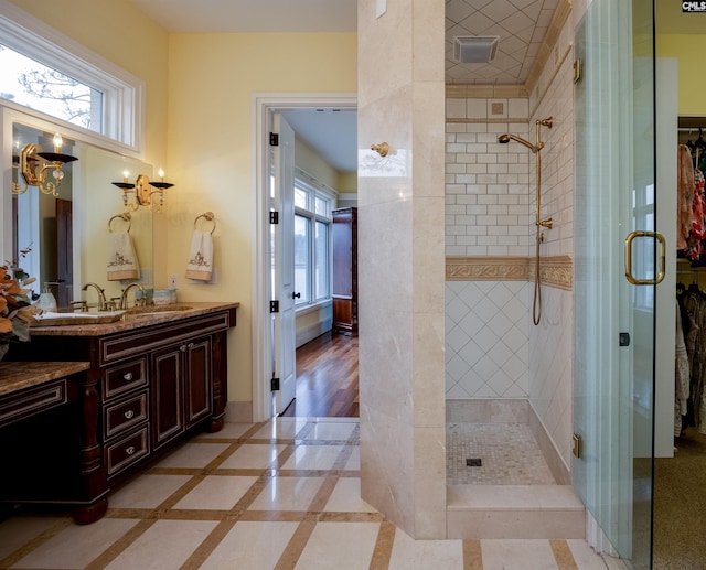 bathroom with vanity, a healthy amount of sunlight, visible vents, and a shower stall
