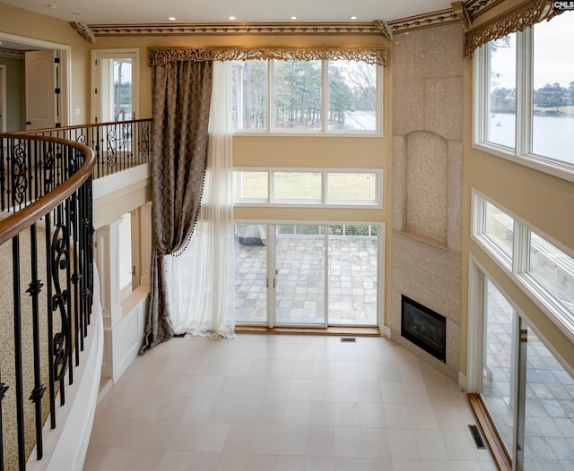 unfurnished living room with visible vents, recessed lighting, a towering ceiling, and a large fireplace