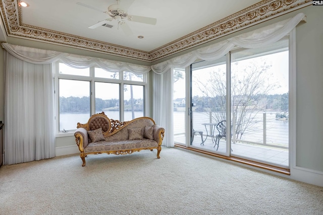 living area with a water view, carpet flooring, and a ceiling fan