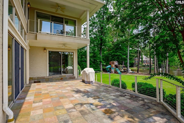 view of patio featuring a balcony, a ceiling fan, area for grilling, and a playground