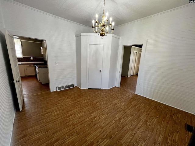 unfurnished dining area with dark wood finished floors, visible vents, a notable chandelier, and ornamental molding