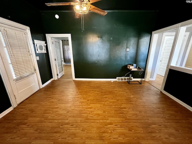 interior space with baseboards, wood finished floors, and a ceiling fan