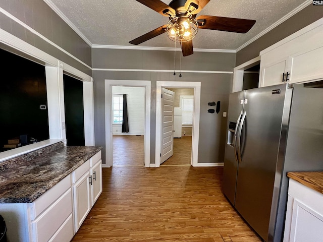 kitchen featuring wood finished floors, stainless steel fridge, a textured ceiling, white cabinets, and ornamental molding