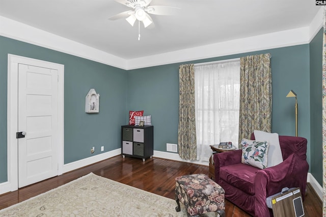 living area featuring baseboards, visible vents, wood finished floors, and a ceiling fan