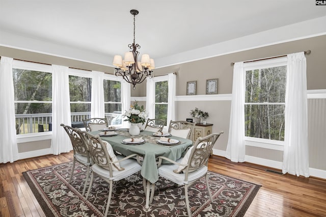 dining area featuring hardwood / wood-style floors, baseboards, a notable chandelier, and a healthy amount of sunlight