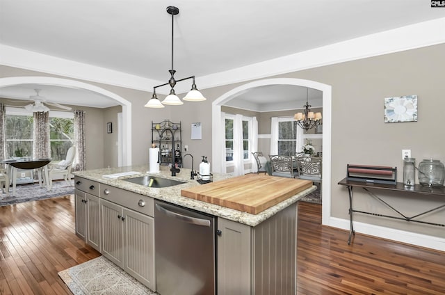 kitchen featuring gray cabinetry, arched walkways, dishwasher, and dark wood-style flooring