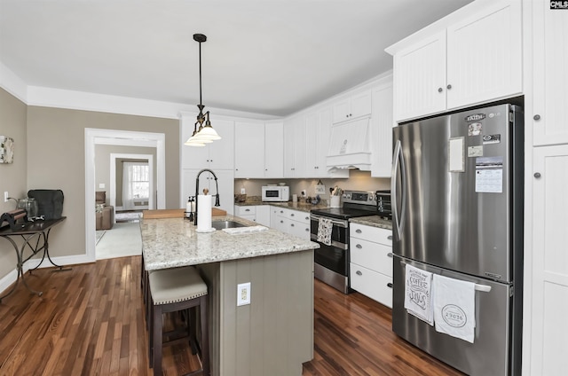 kitchen with white cabinetry, dark wood-style flooring, a sink, a kitchen island with sink, and appliances with stainless steel finishes