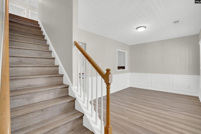 1827 Lake Carolina Dr, Columbia, SC 29229 - staircase featuring visible vents, wood finished floors, a decorative wall, and wainscoting