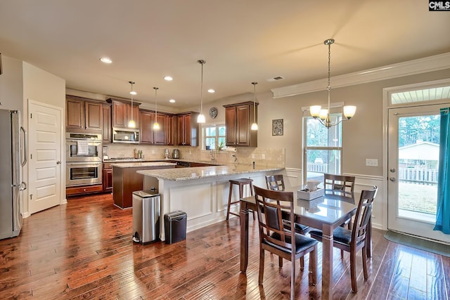 dining space featuring dark wood-style flooring, a wainscoted wall, a chandelier, ornamental molding, and recessed lighting