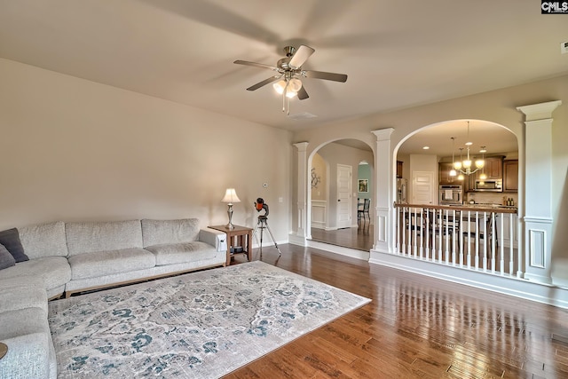living room with arched walkways, ceiling fan, wood finished floors, and ornate columns