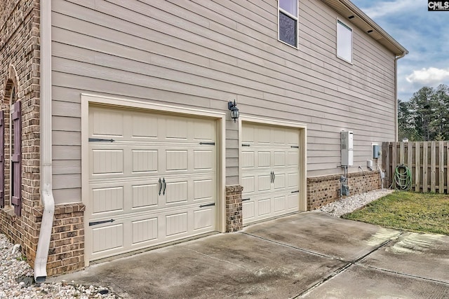 garage with fence and concrete driveway