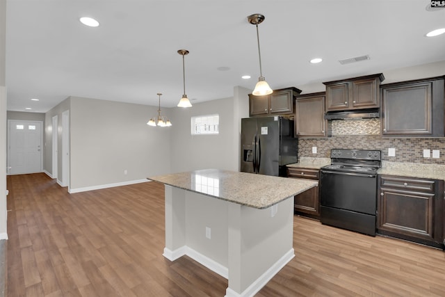 kitchen with light wood-type flooring, under cabinet range hood, visible vents, black appliances, and dark brown cabinets