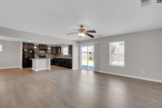 unfurnished living room featuring baseboards, visible vents, light wood-type flooring, and a ceiling fan