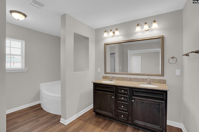 full bath featuring a sink, wood finished floors, and a bathing tub