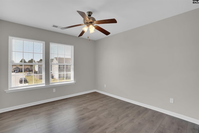 empty room featuring baseboards, visible vents, a ceiling fan, and dark wood finished floors