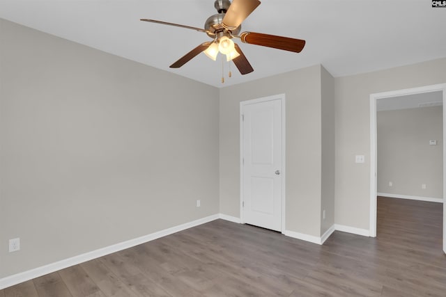 spare room featuring baseboards, wood finished floors, and a ceiling fan