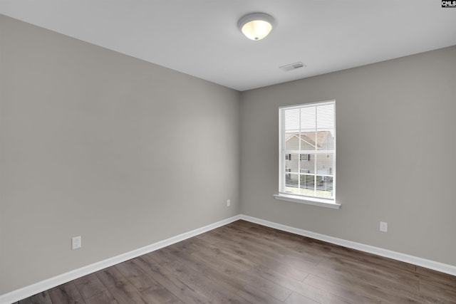 spare room featuring dark wood-style floors, baseboards, and visible vents
