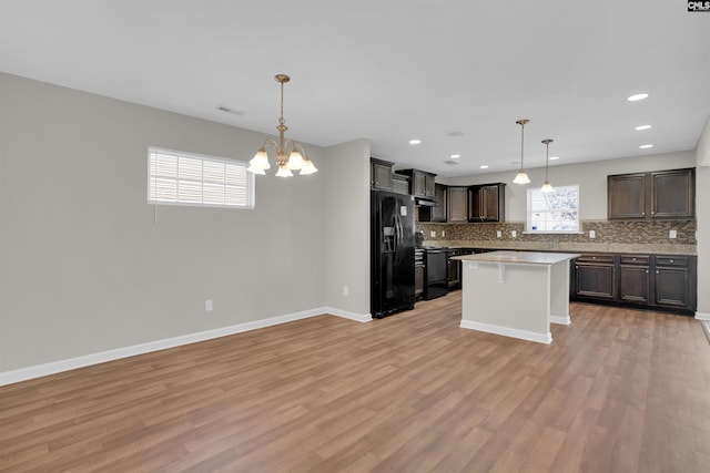 kitchen featuring light countertops, tasteful backsplash, black appliances, and light wood-type flooring