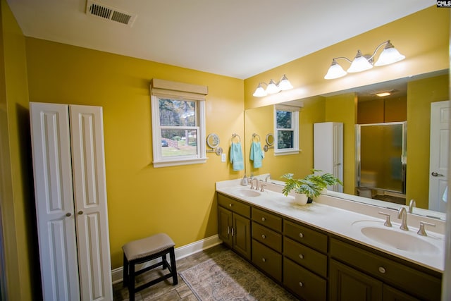 bathroom with double vanity, a sink, a stall shower, and visible vents