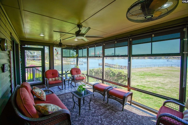 sunroom with a ceiling fan and a water view