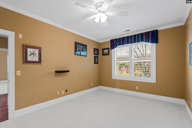spare room featuring crown molding, carpet flooring, baseboards, visible vents, and ceiling fan