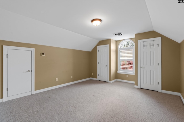 bonus room with lofted ceiling, baseboards, light colored carpet, and visible vents