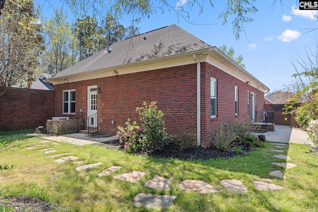 back of house featuring fence, a patio area, brick siding, and a lawn