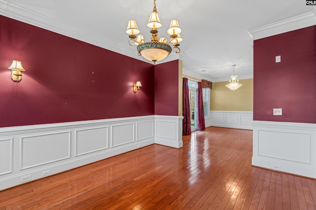 unfurnished room featuring a wainscoted wall, a notable chandelier, ornamental molding, and hardwood / wood-style flooring