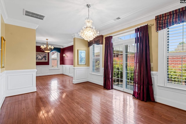 spare room with an inviting chandelier, wood-type flooring, and visible vents